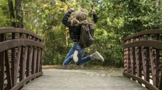 Young person crossing a bridge jumping with excitement